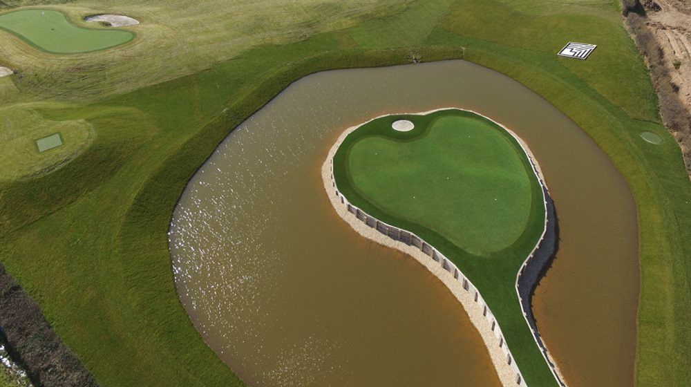 San Francisco Aerial view of a vibrant green synthetic grass island in a natural pond on a golf course