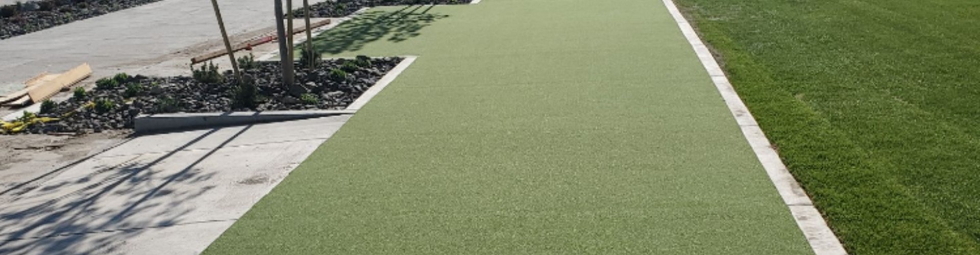 Artificial turf tee lines installed along a landscaped golf practice area, providing durable, low-maintenance synthetic grass surfaces ideal for consistent tee shots and heavy foot traffic.